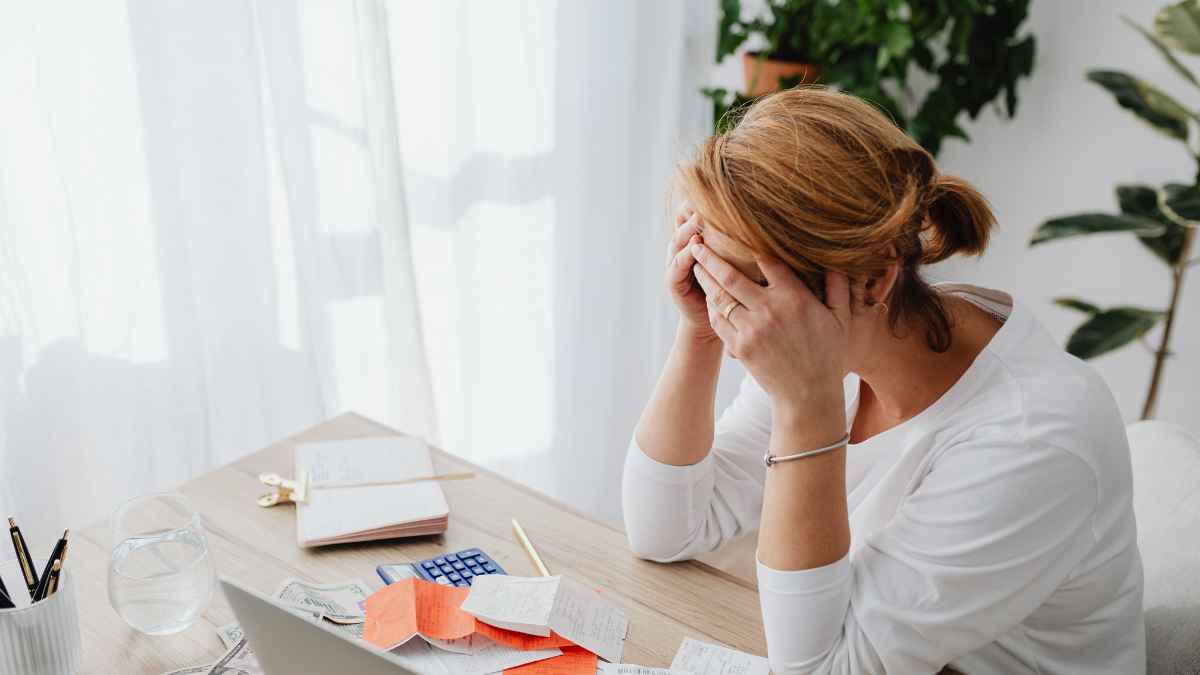 Small business owner reviewing stacked merchant cash advance payments and daily ACH debt